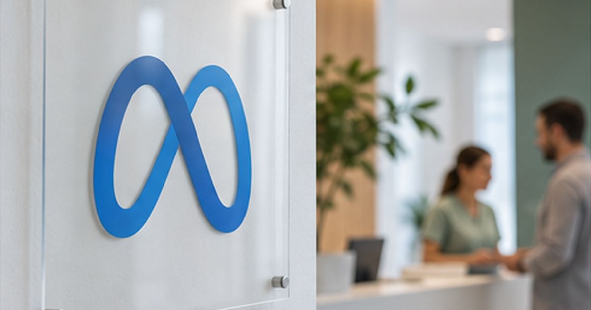 Logotipo de Meta en un panel de cristal de una recepción, con dos personas hablando al fondo